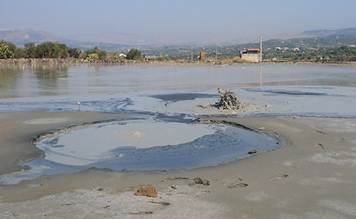 Salinelle dei Cappuccini (Paternò, CT), attività parossistica con gorgogliamento di gas e acque fangose. Si nota uno spesso strato scuro di idrocarburi oleosi, portati in superficie dai fluidi profondi, che galleggiano sull'acqua