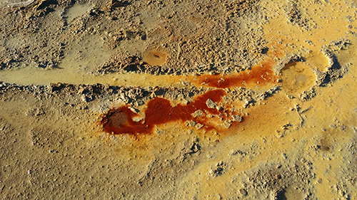 Emissioni salmastre alle Salinelle dei Cappuccini (Paternò) con concrezioni e depositi minerali costituiti da ossidi e idrossidi di ferro (in rosso-mattone), solfuri (giallo-ocra) e carbonati di tipo travertinoso frammisti a fango (grigio-marrone)